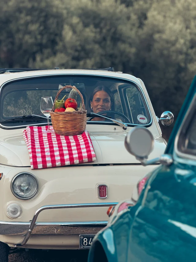 Guests enjoying a cream vintage Fiat 500 with a picnic basket
