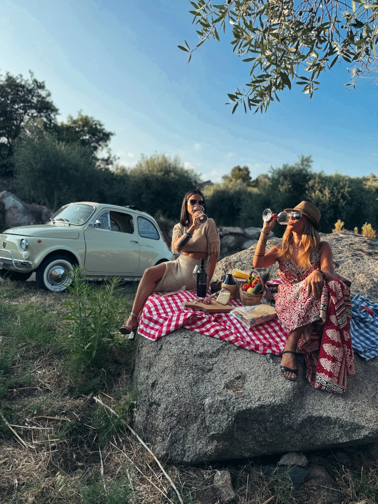Guests sharing an aperitivo beside a vintage Fiat 500 in a green Sardinian setting